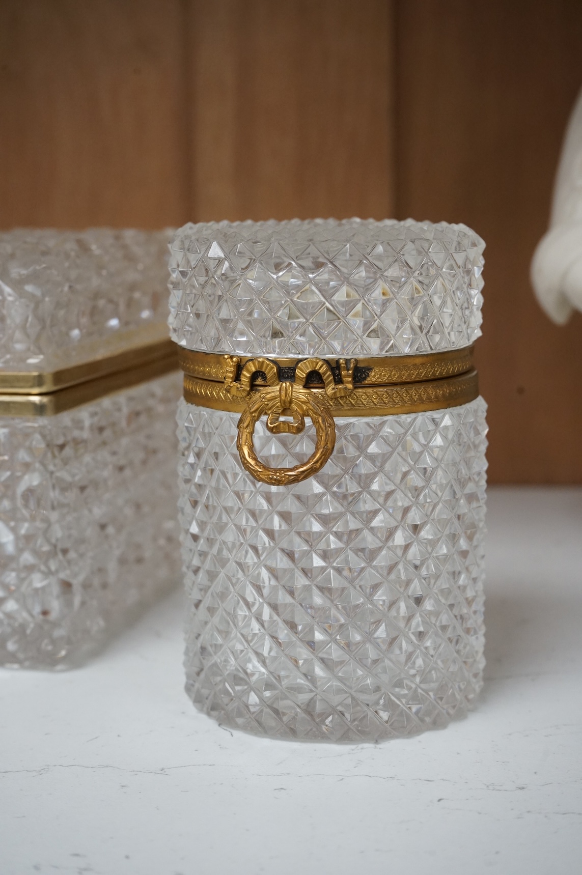 A deeply cut rectangular glass casket, a similar smaller casket and a cylindrical container, all with gilt metal mounts, largest 18cm wide x 10.5cm high.